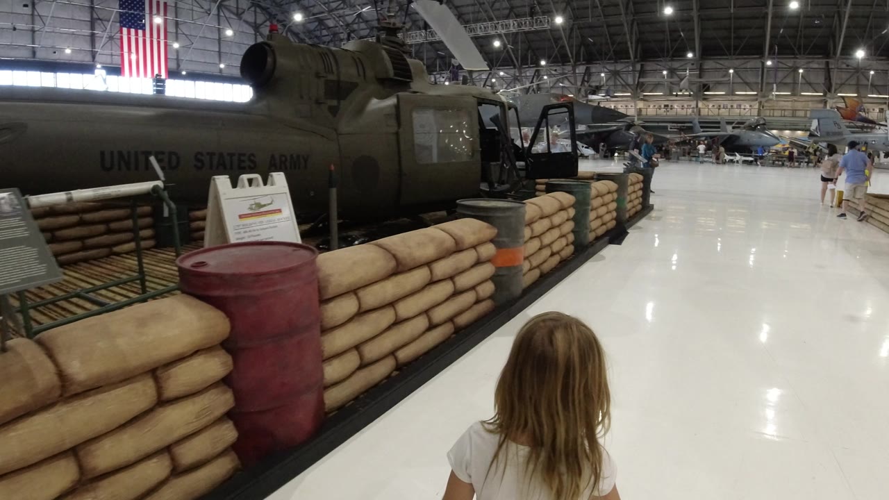 Child walking toward a military display inside a hangar museum.
