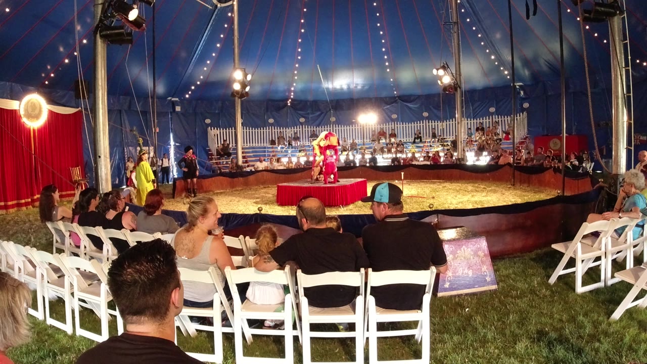 Small tent performance with audience seated in white chairs