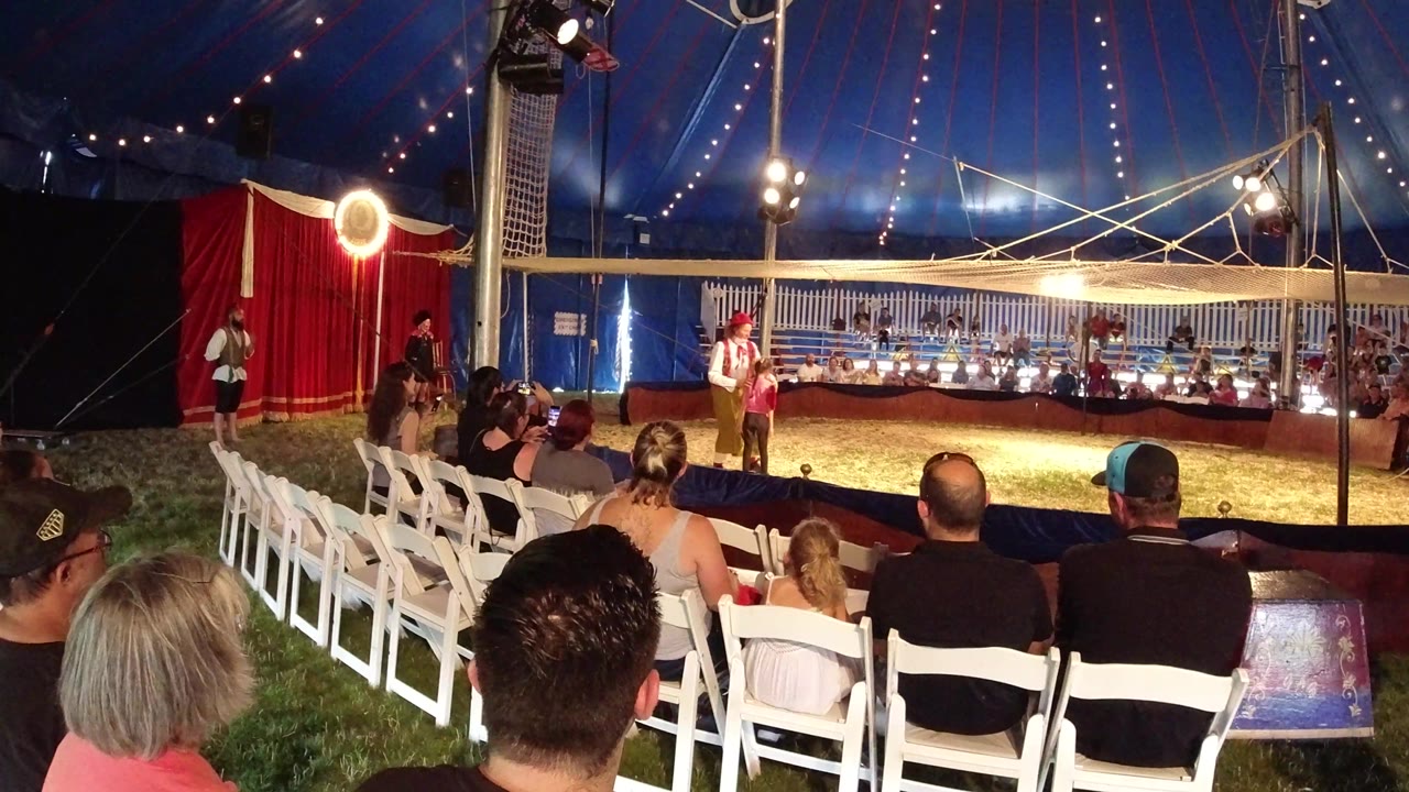In Broomfield, Colorado, the clown remains in the lit ring while the seated audience fills the foreground and tent poles divide the view.