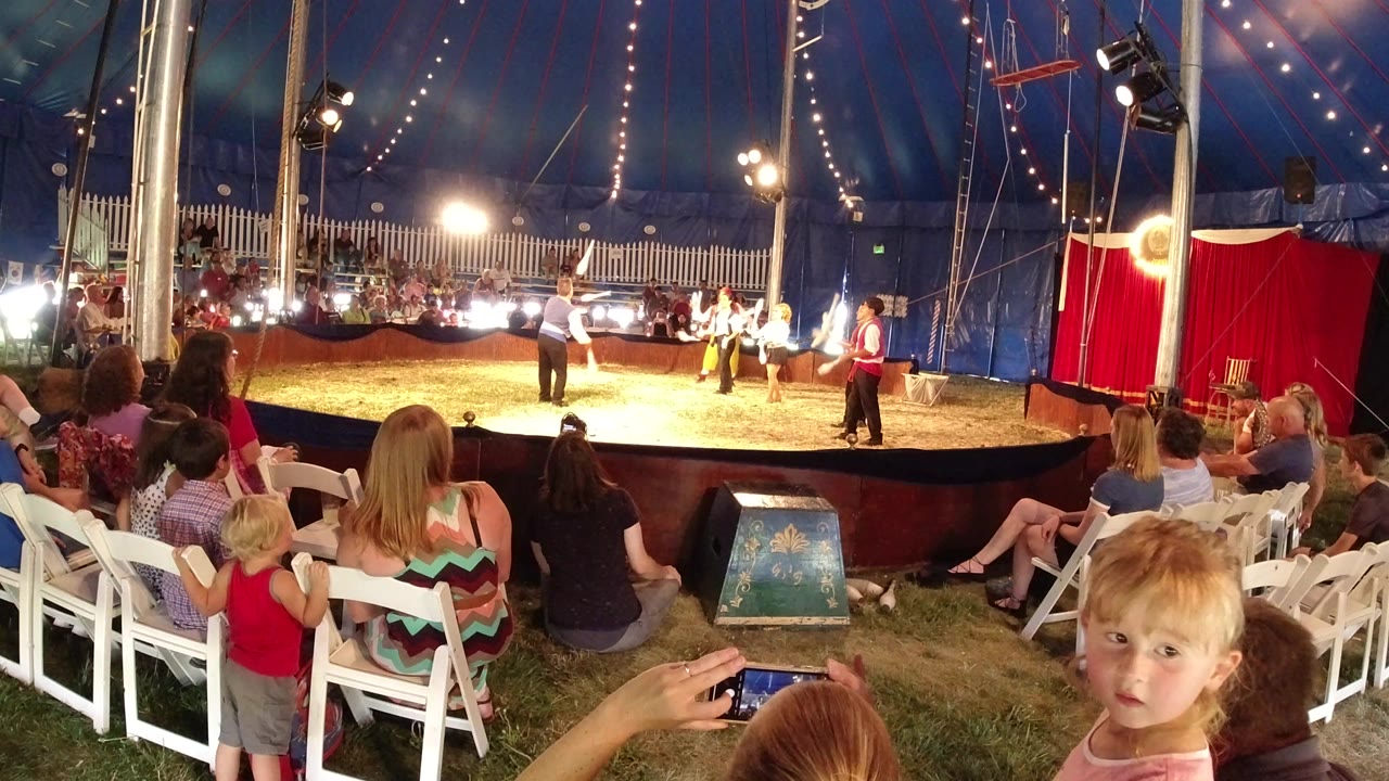 Families watch from white chairs while performers in the ring move under bright bulbs and rigging inside the Broomfield, Colorado tent.
