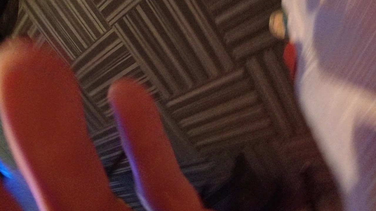 Close fingers partly covering a downward view of patterned carpet.