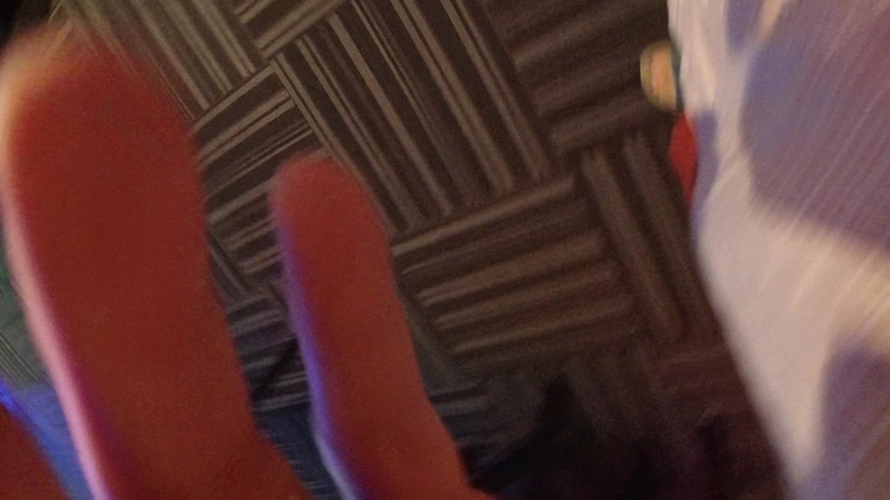 A blurred close view in Broomfield, Colorado shows fingertips, a white shirt edge, and dark patterned carpet beneath the camera.