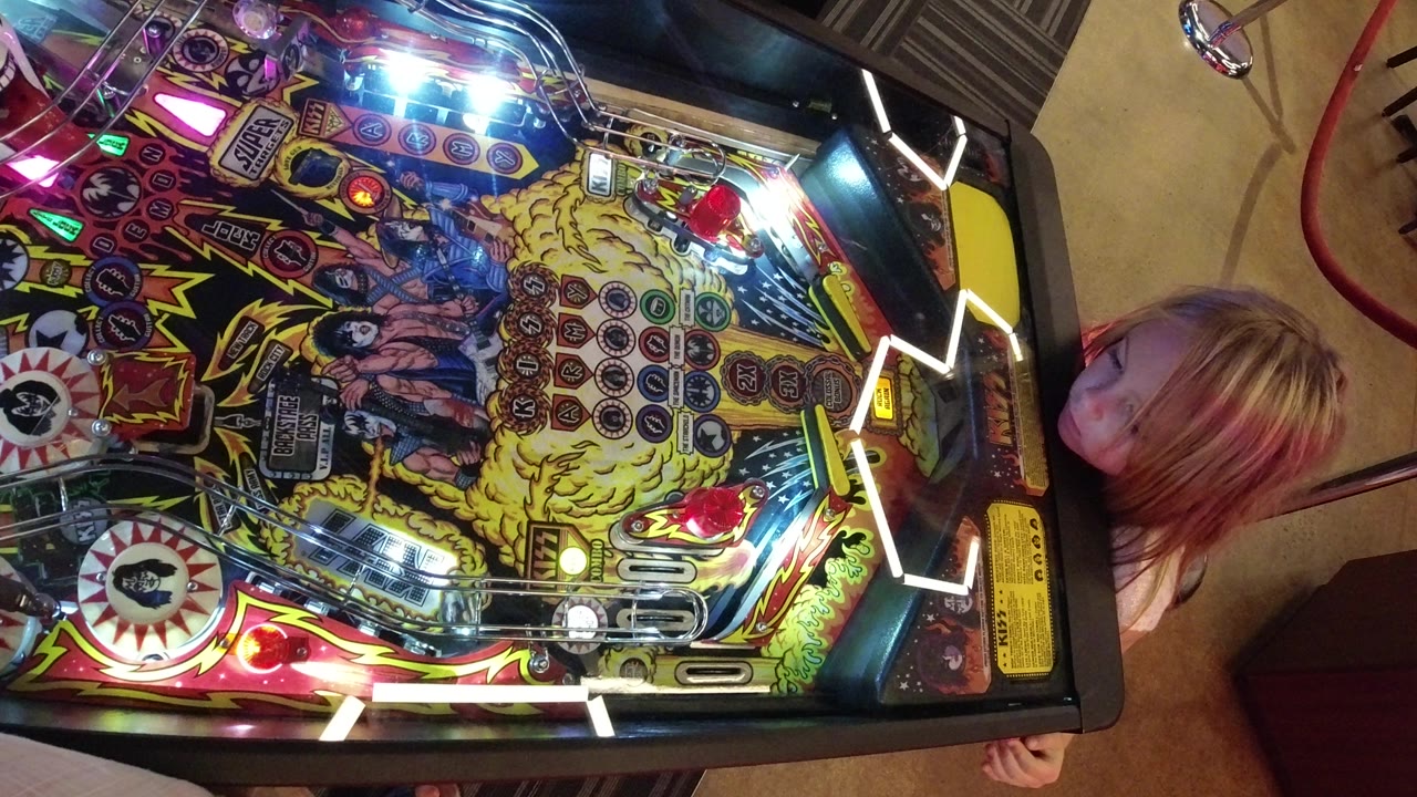 Close overhead frame of the pinball machine playfield in Broomfield, Colorado, with the child’s face and hair partially cropped along the right side.
