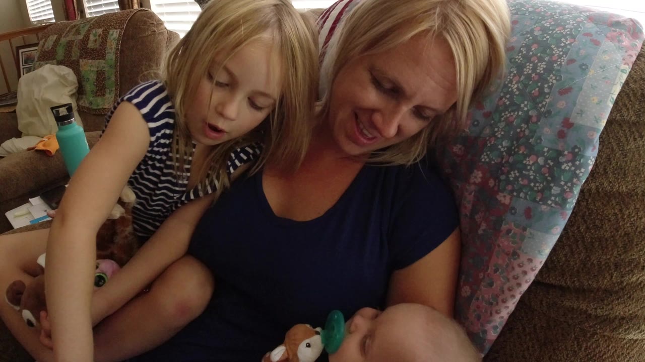 In Broomfield, Colorado, a blonde woman smiles beside a young blonde child on a couch while a baby appears at the bottom of the frame.
