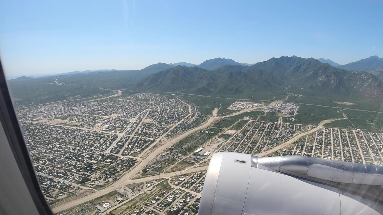 Airplane engine over city streets and mountains