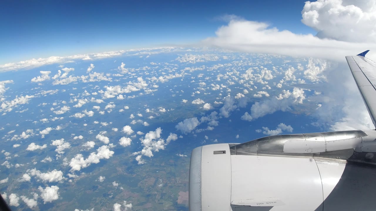 Airplane wingtip and engine above a cloud layer.
