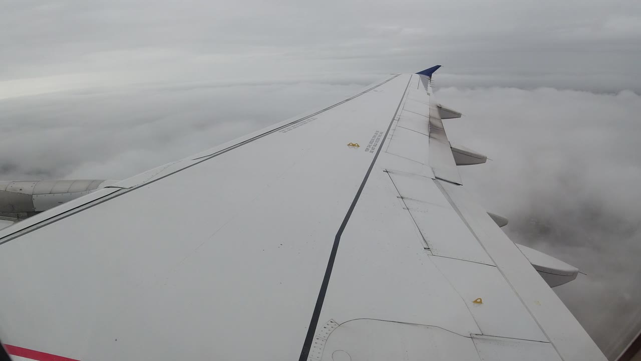 The aircraft wing remains prominent over Los Cabos, Mexico as the cloud bank thickens near the horizon, with no visible people.