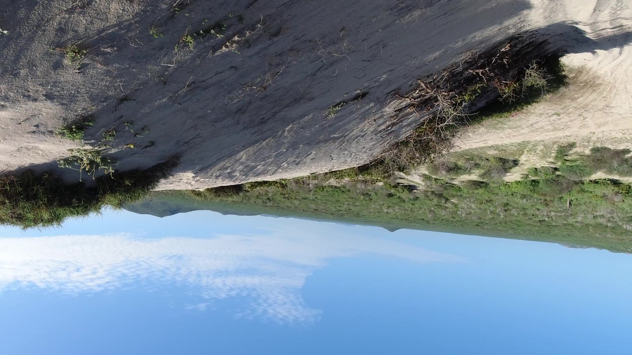Upside-down mountain slope with dry brush and sky