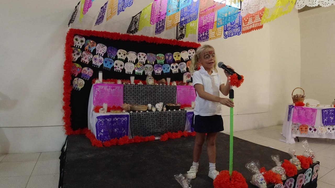 Child in Halloween face makeup standing by a green microphone stand