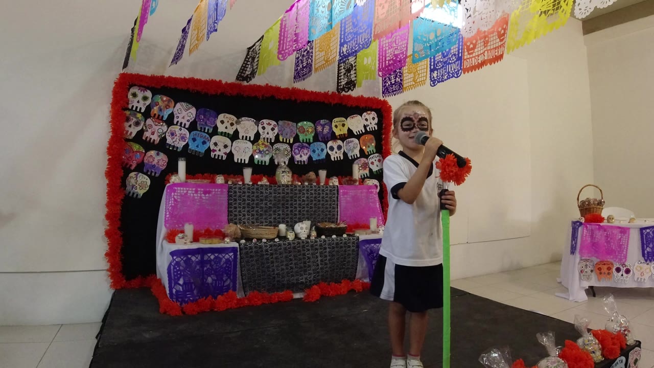 Boy with face paint holding a green microphone stand beside a decorated skull display.
