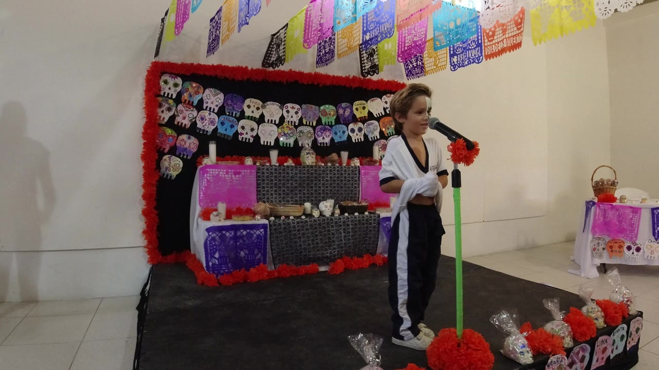Child standing at a microphone on a decorated indoor stage.
