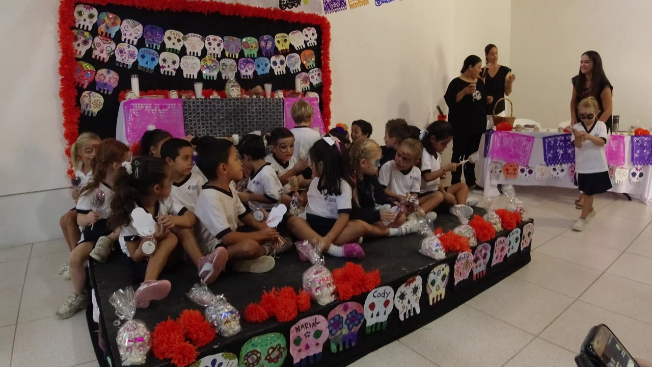 Children in school uniforms seated on a decorated platform during a school program.