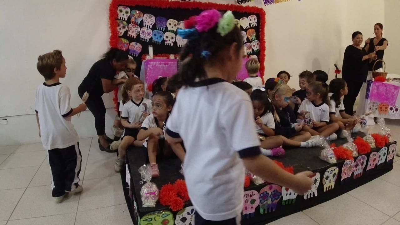 Children and adults gather around a decorated school platform.