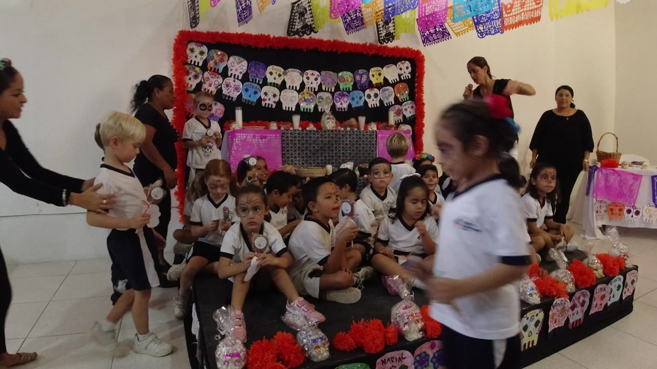 Children in school uniforms gather on a decorated platform as adults arrange them.