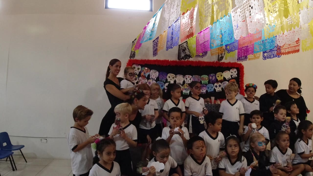 Children and teachers gathered in front of colorful classroom decorations.