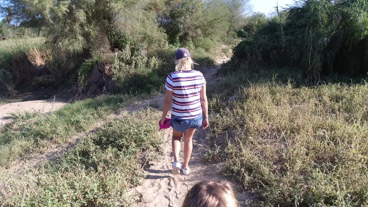 Adult walking away on a sandy path with a child's head at the bottom edge.
