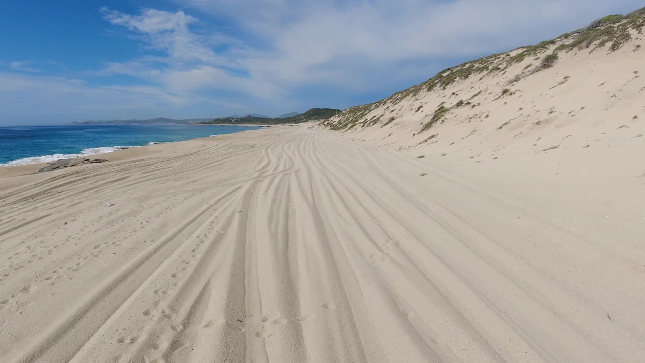 Rutted sand path between ocean and dune ridge.