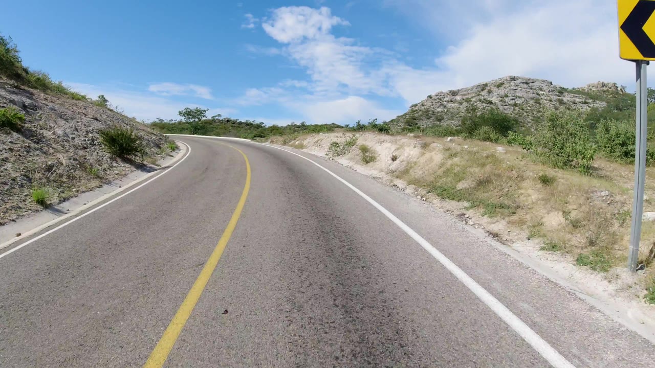 Empty mountain road with large curve sign at right edge