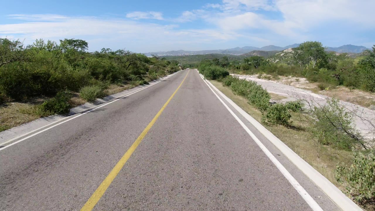 Road cresting gently through desert brush with hills ahead.