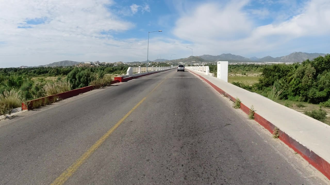 Bridge approach with white railing and mountain background