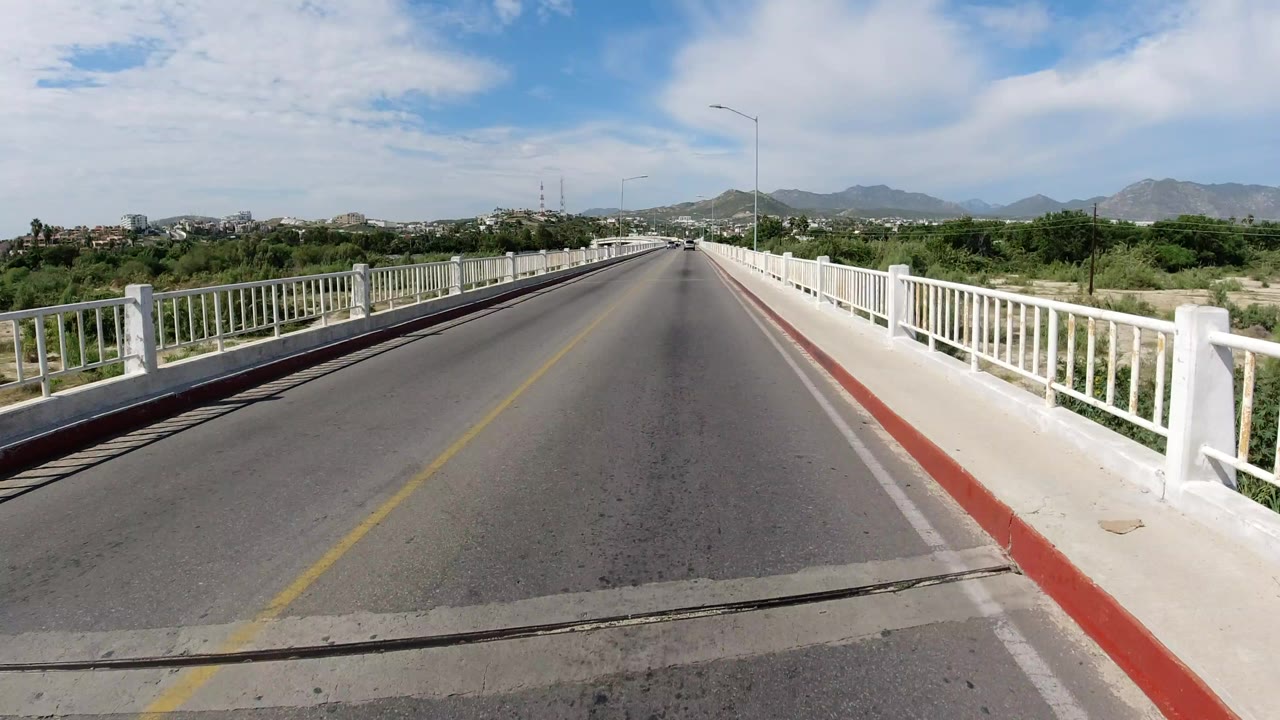 Empty bridge roadway with white railings and distant mountains