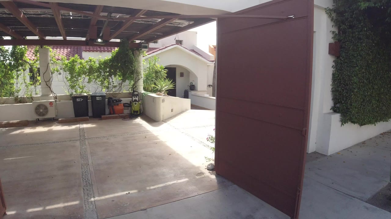 Covered patio with plants, trash bins, and a red door edge.