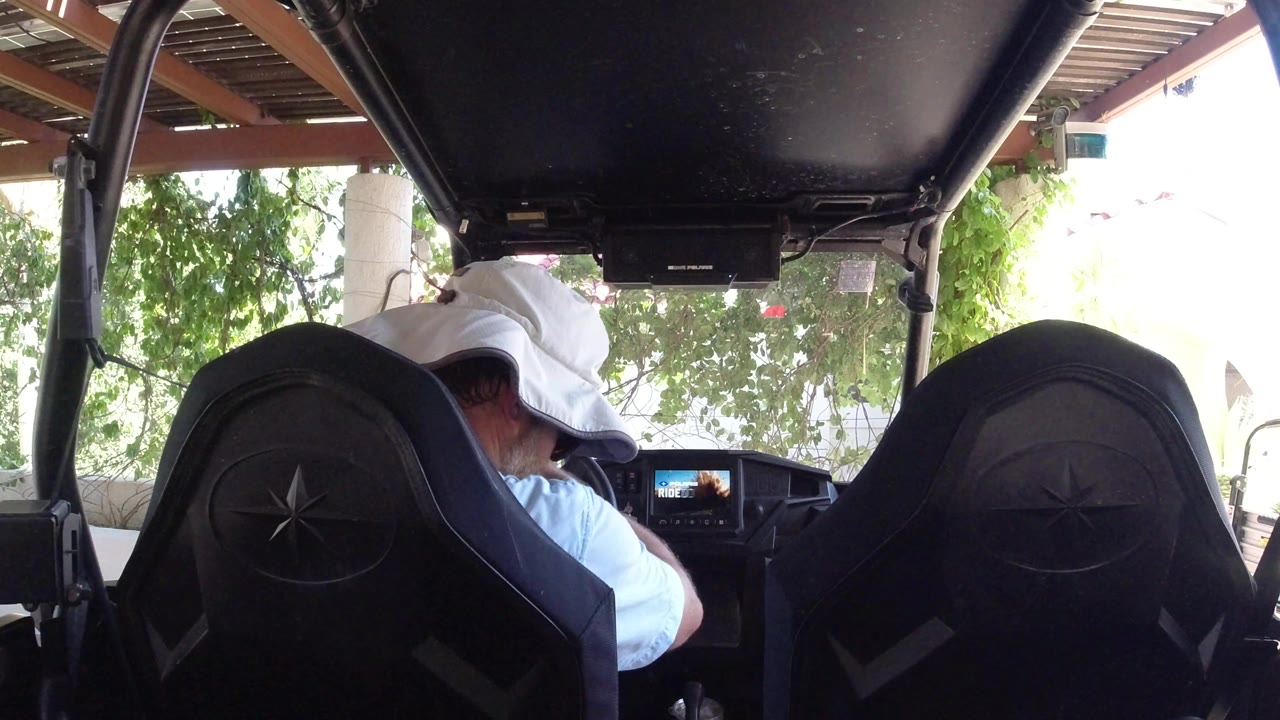 Man in white cap seated inside a black vehicle interior