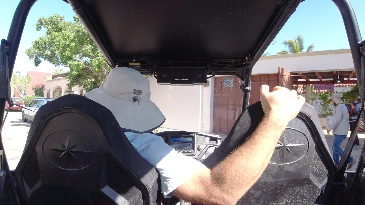 Driver in a white hat seen from behind inside a buggy.