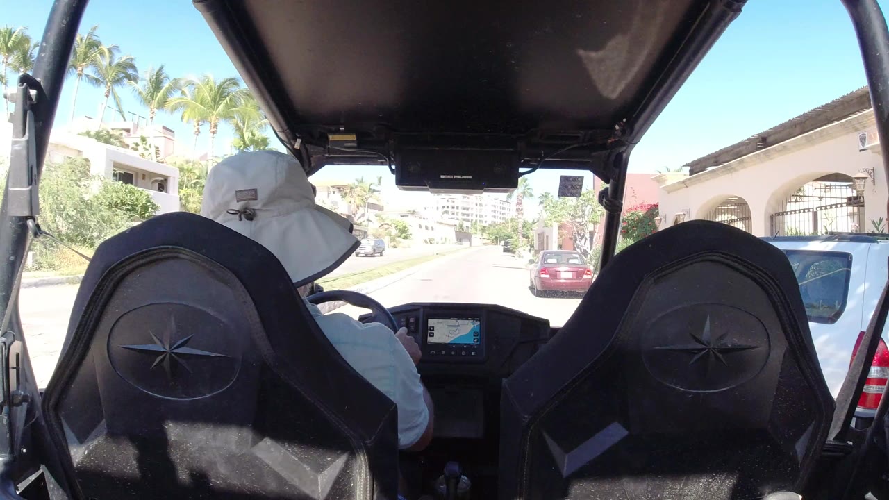 Back seat view inside an open go-kart on a sunny residential street.