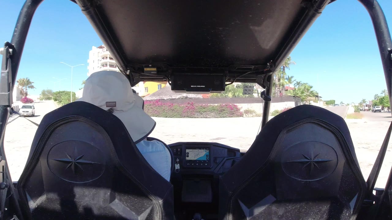 Back-seat view inside an open vehicle on a bright street.