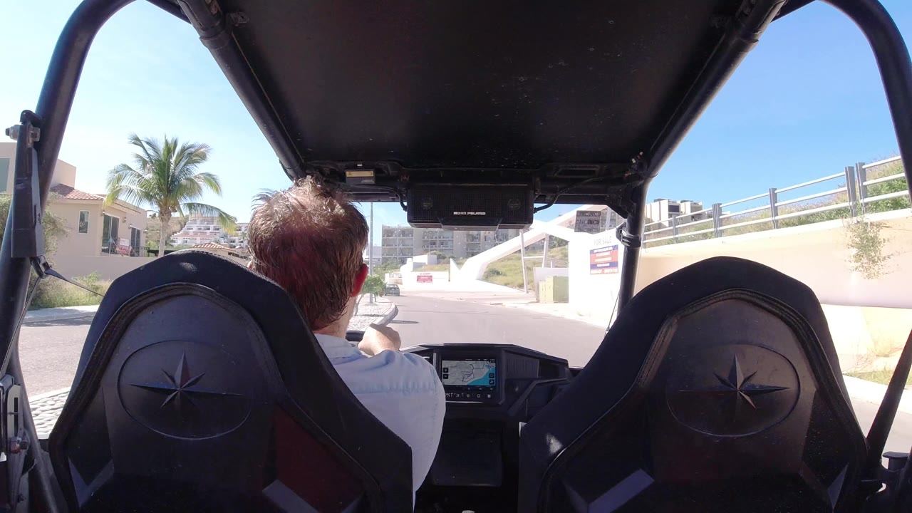 Rear passenger view inside a covered vehicle on a sunny road.