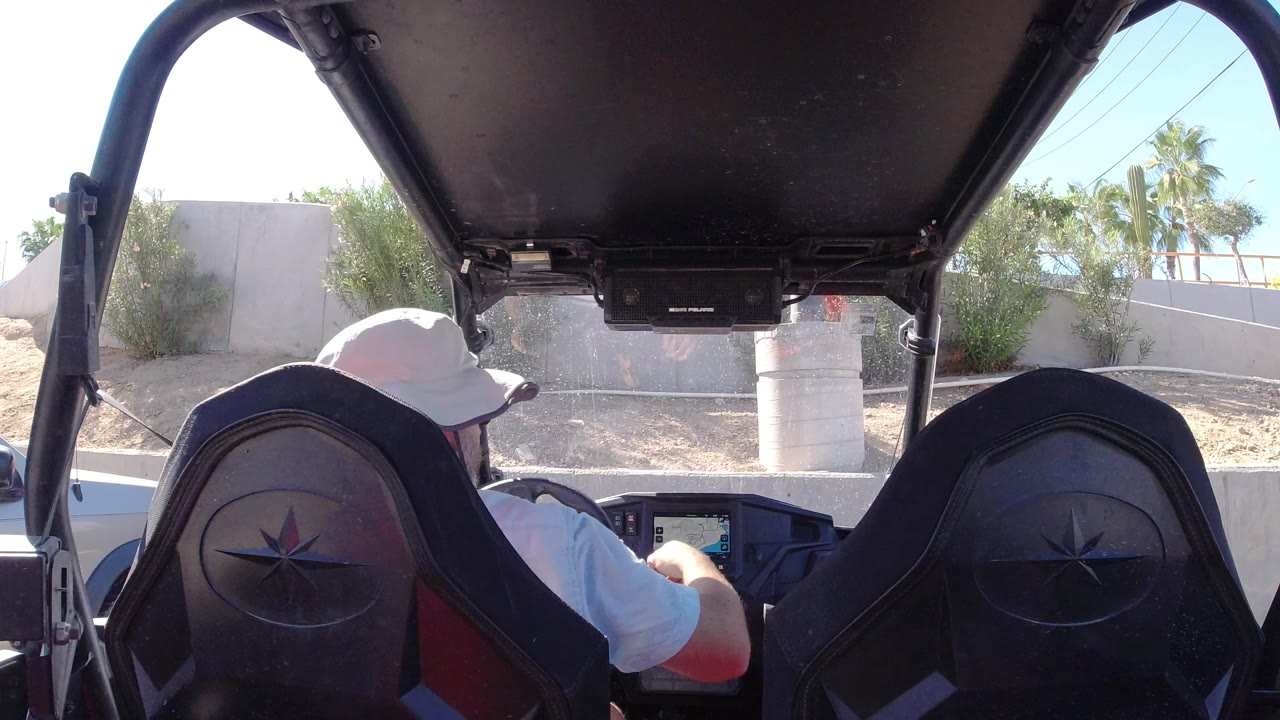 Driver in a white cap seated inside a covered off-road vehicle.