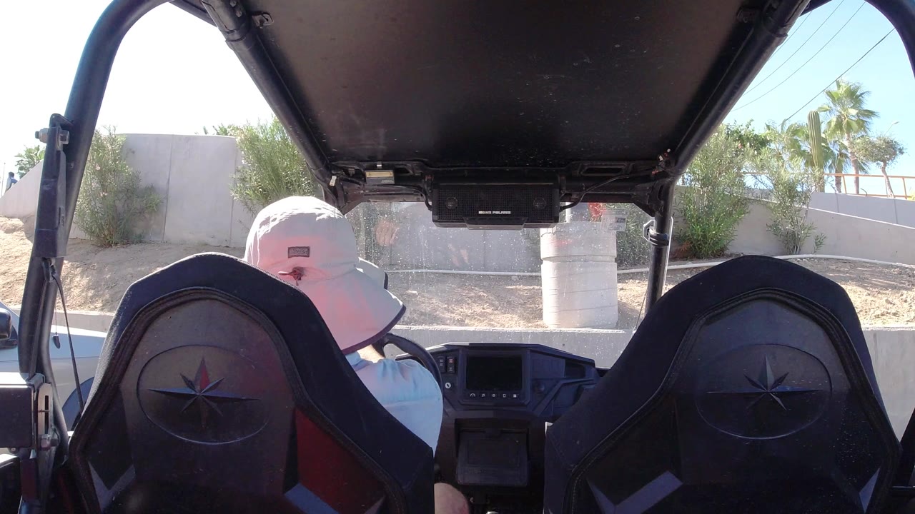 Person in a white hat seated in an open vehicle interior.