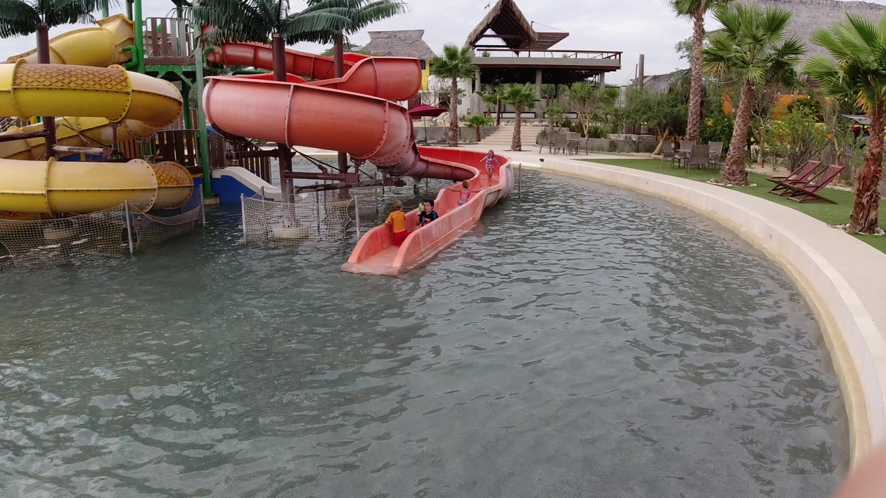 Red and yellow water slides ending in a pool with riders visible