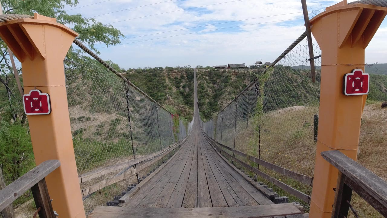 Wooden bridge walkway leading across a dry valley.