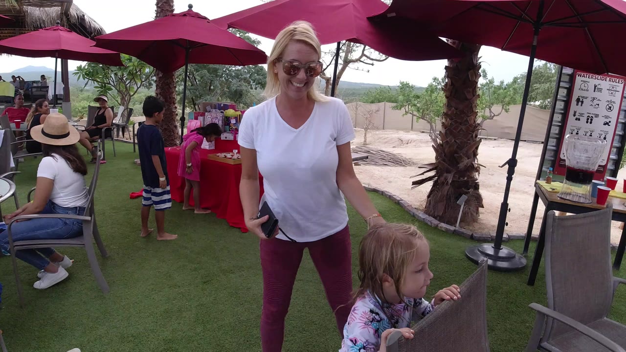 Woman in sunglasses standing beside a little girl at an outdoor fair table.
