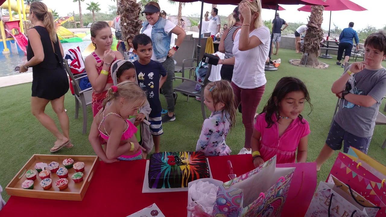 Children and adults around a cupcake table at a water park.
