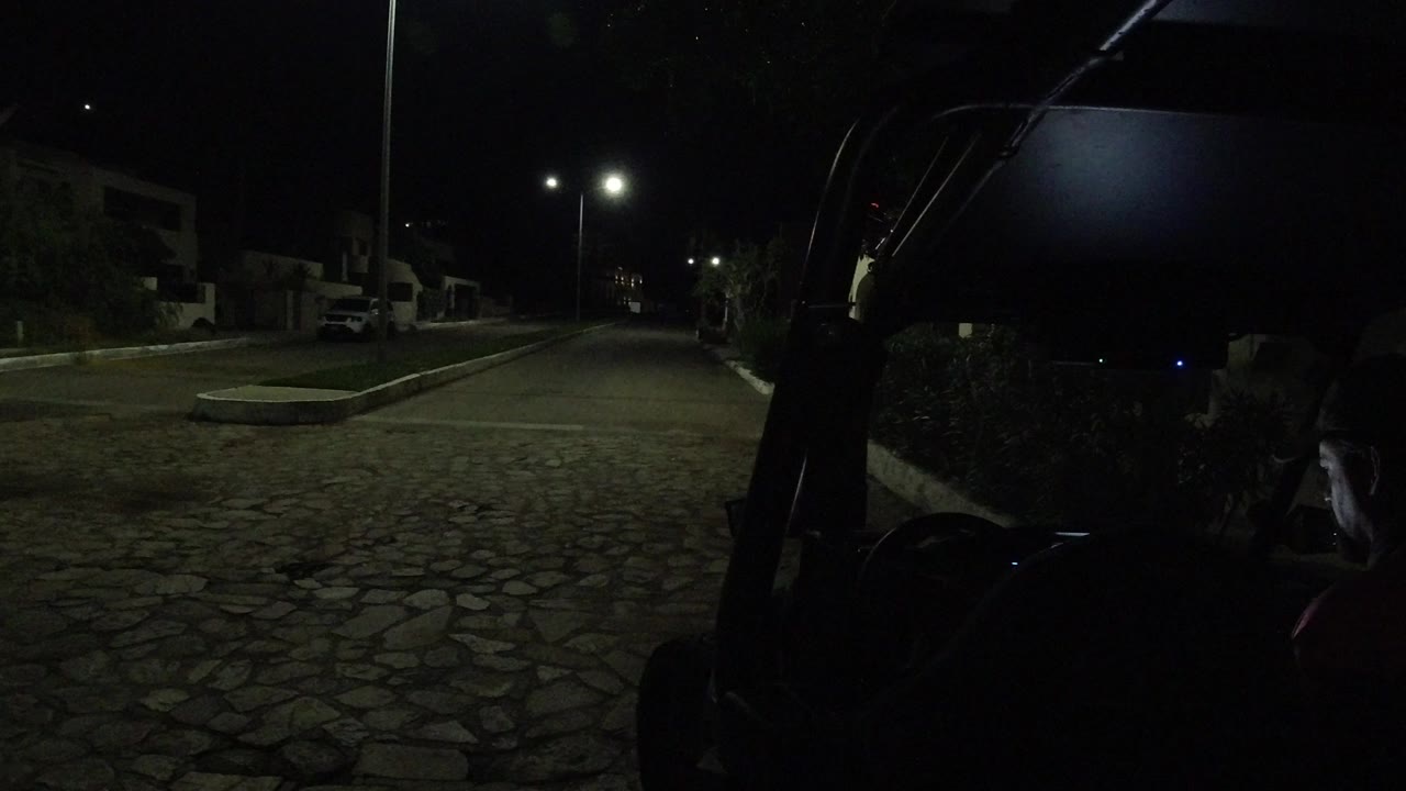 Dark cobblestone street beside a parked vehicle at night.