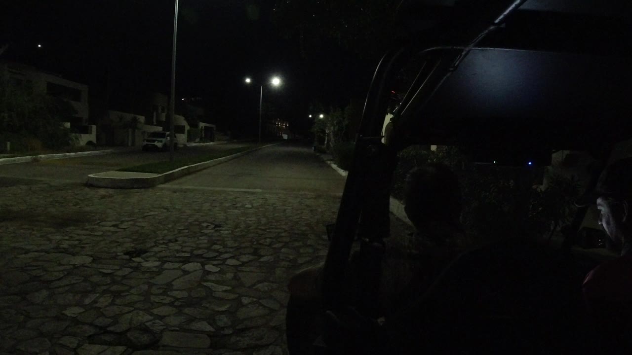 At 0:01 in Los Cabos, Mexico, the dark Wrangler interior and two seated men remain in the foreground as a pair of bright streetlights marks the road ahead.