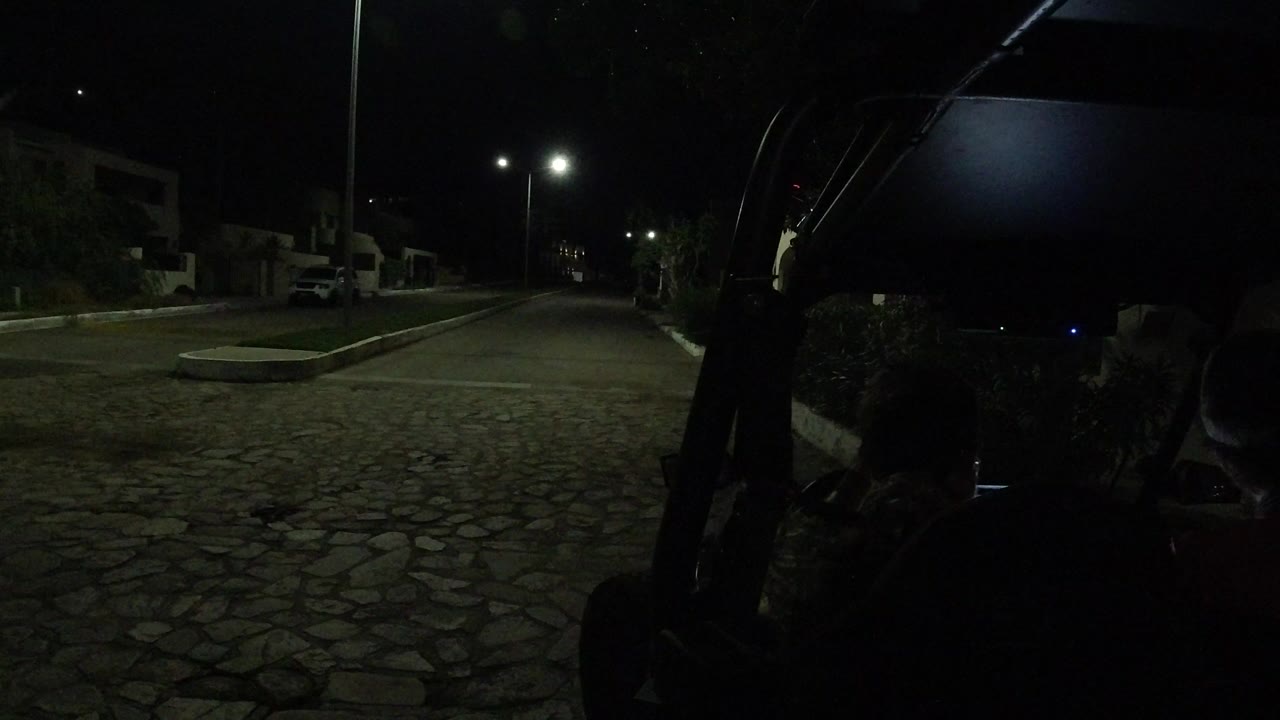 Opening frame in Los Cabos, Mexico showing a dark stone-paved road, streetlights, parked vehicles, and silhouetted people beside a stopped Wrangler.
