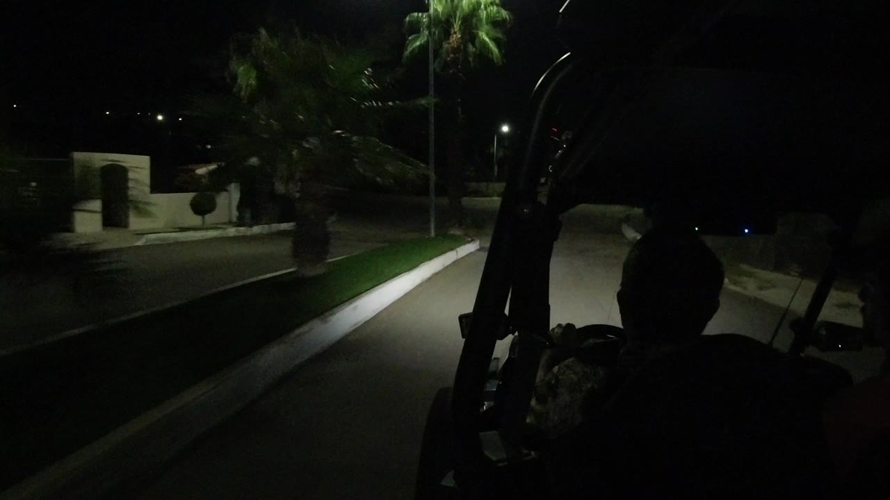 Dark residential road seen from behind two men in a Jeep Wrangler.