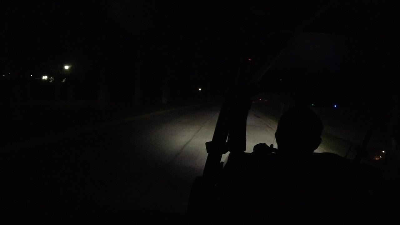One second in, the driver remains in shadow as the headlight beam reaches farther down the dark Los Cabos roadway with a few small lights in the distance.