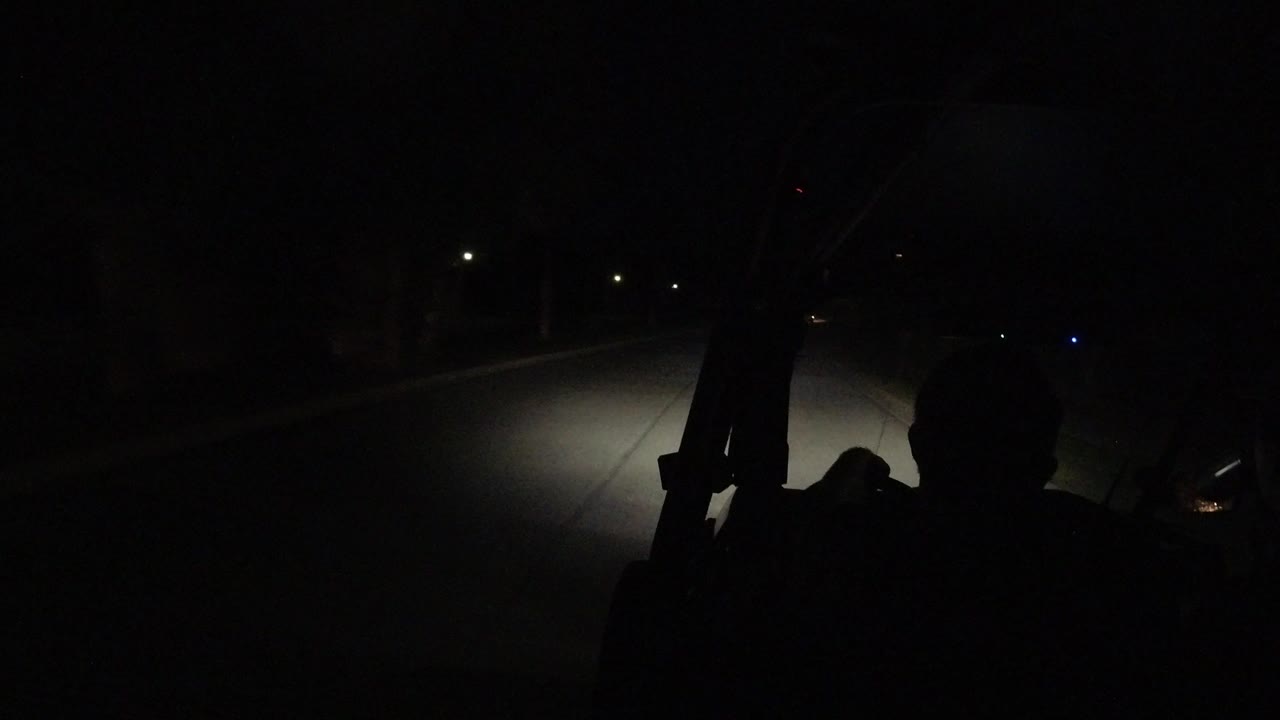 Dark road seen from inside a vehicle with passenger silhouettes.