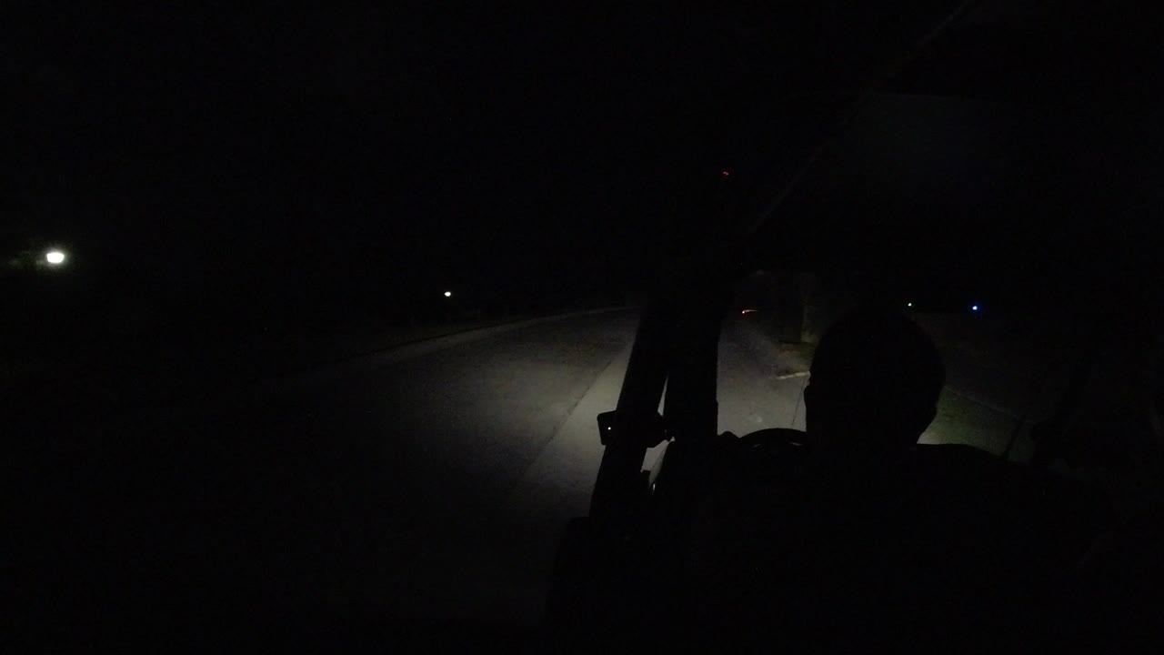 Opening frame of a dark Los Cabos, Mexico highway scene, with headlights lighting the road curve and no visible people.
