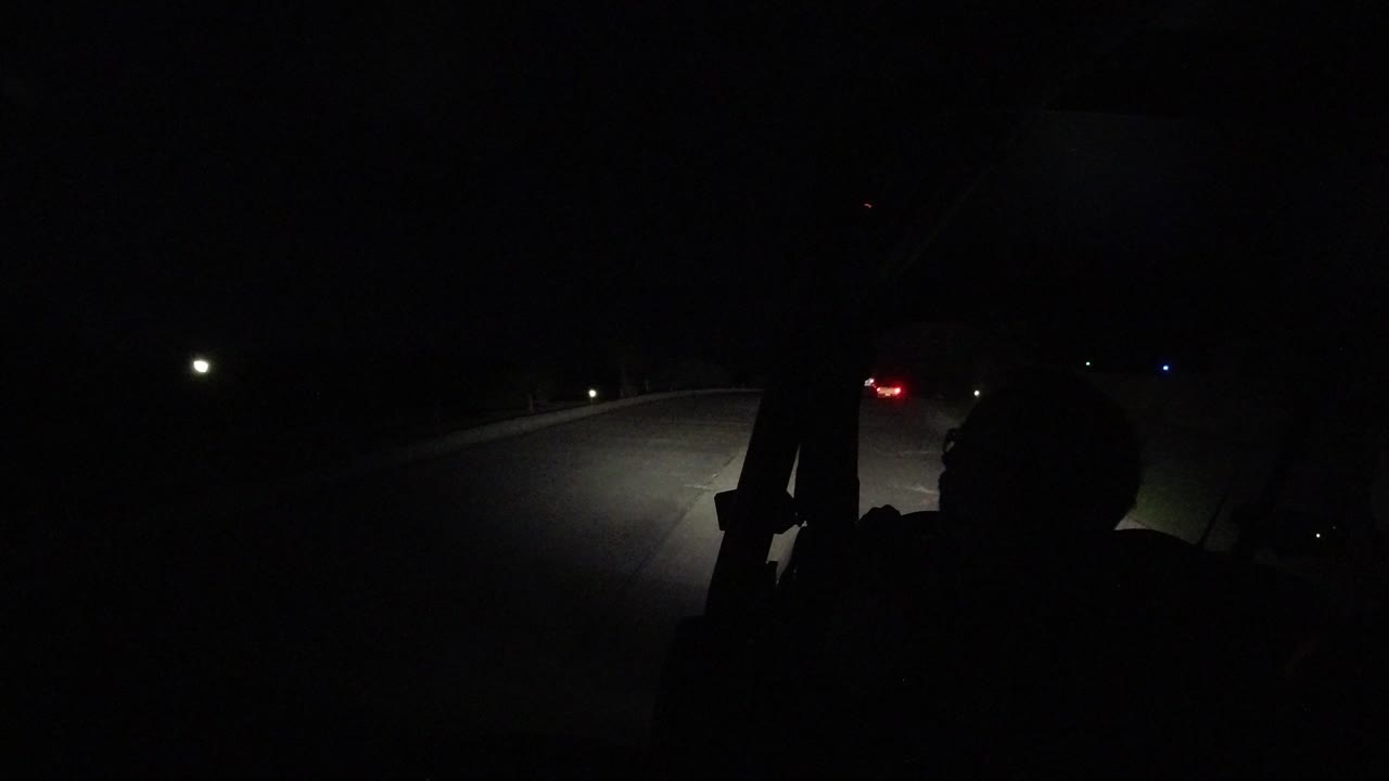 Dark highway curve with small red taillights ahead