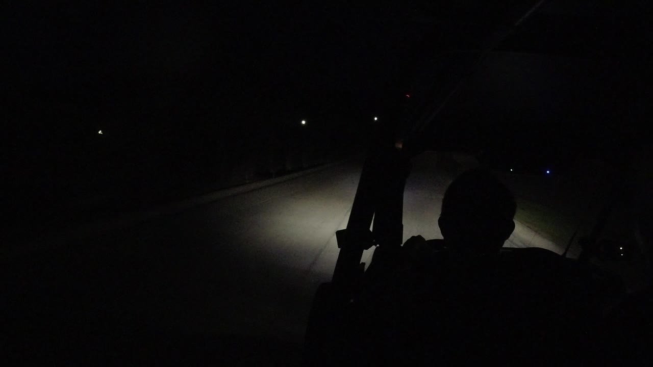 Dark road seen from a vehicle with a silhouetted person in front