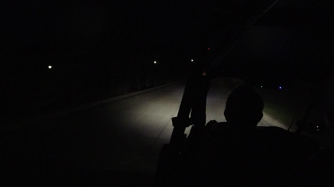 At 0:01 in Los Cabos, the headlight beam falls across the road while the foreground person remains a dark, unidentifiable silhouette.