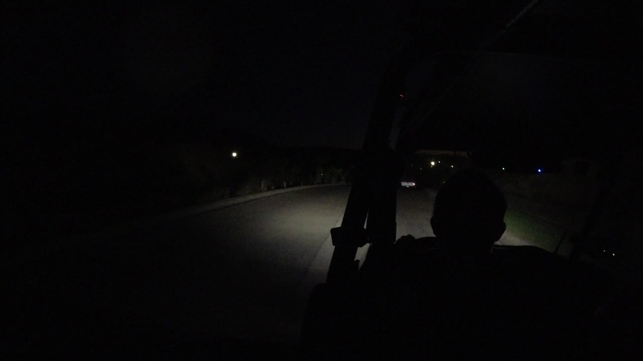At 0:01, the silhouetted rider remains in the foreground as the golf cart headlights spread across the dark road in Los Cabos, Mexico.