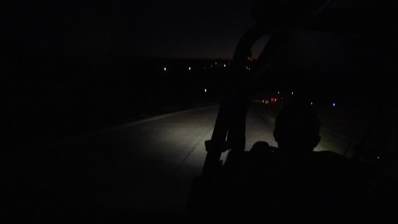 Dark road seen past a silhouetted driver and vehicle frame.