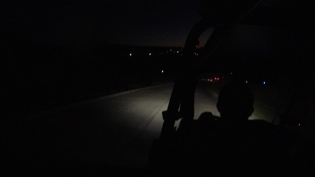 At 0:01, the driver remains a dark shape in the lower frame while the headlights reveal the paved road and faint roadside edge in Los Cabos, Mexico.